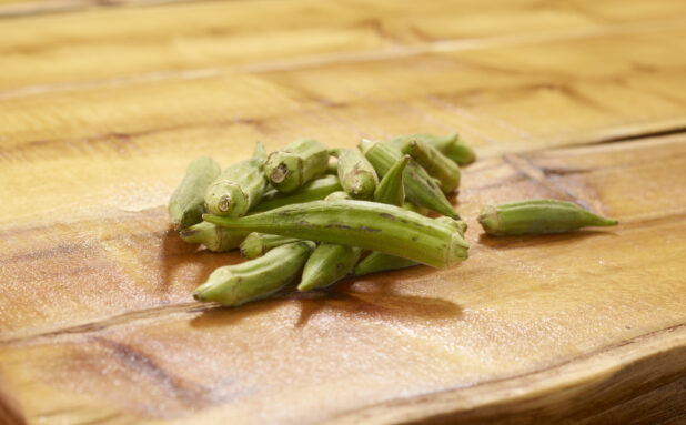 Whole Raw Okra Piled on a Wooden Table