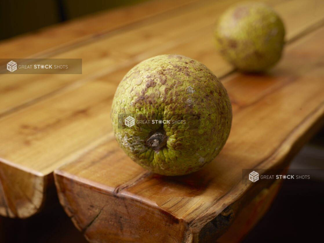 Whole Raw Tropical Breadfruits on Wooden Table with Bokeh Effect