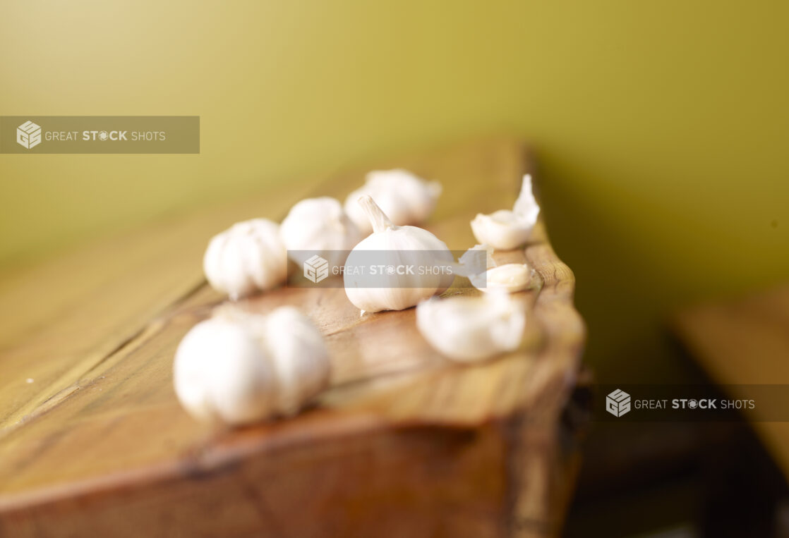 Raw, Unpeeled Cloves of Garlic on Wooden Table with Green Background and Bokeh Effect