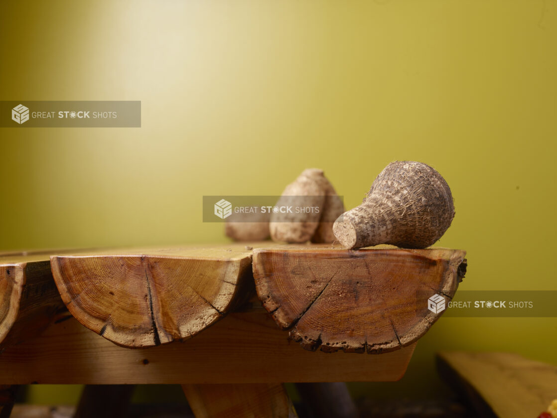 Raw Taro Root on Wooden Table with Green Background and Bokeh Effect - Variation