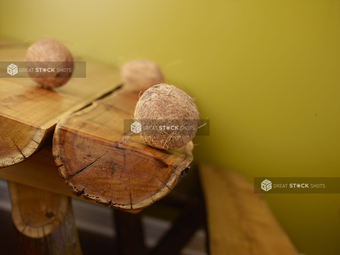 Fresh Whole Coconuts on Wooden Log Table with a Green Background and Bokeh Effect