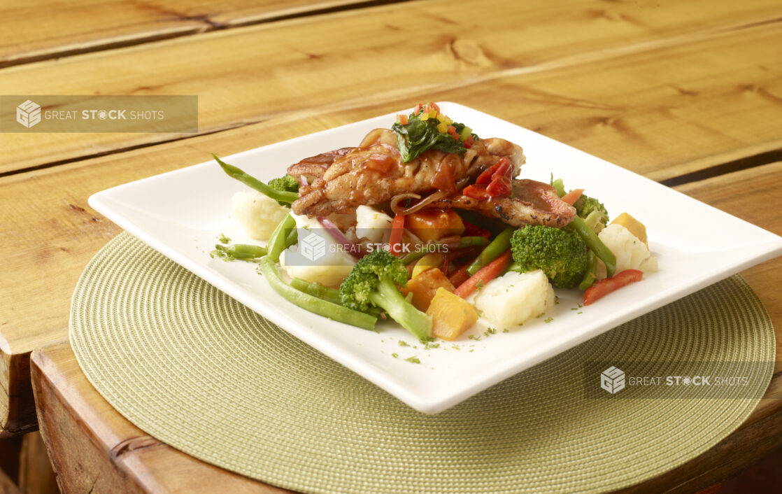 Fried White Fish with Broccoli and Sautéed Vegetables on a Square White Plate on a Green Placemat on a Wooden Table - Variation