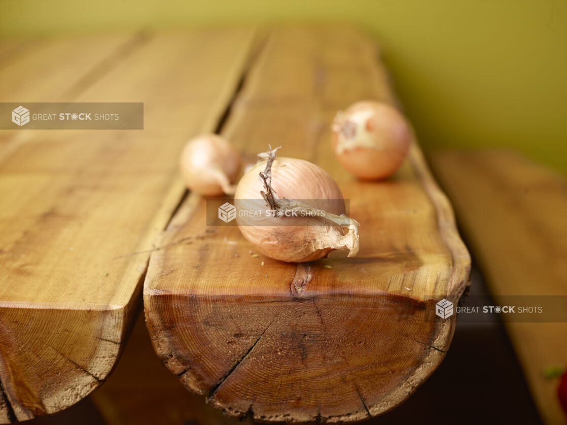 Whole Fresh Yellow Onion Bulbs on Wooden Table with Green Background and Bokeh Effect