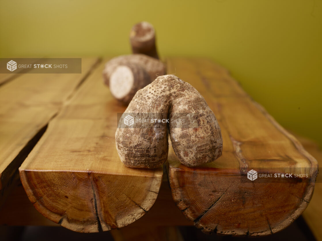 Raw Taro Root on Wooden Table with Green Background and Bokeh Effect – Variation 2