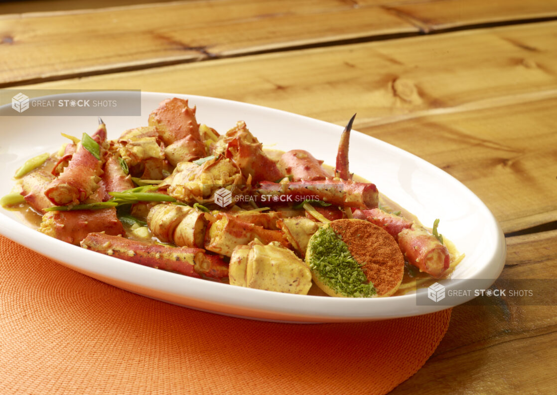 Caribbean King Crab Stew with Cracker on Large White Platter on Orange Placemat on Wooden Table - Variation