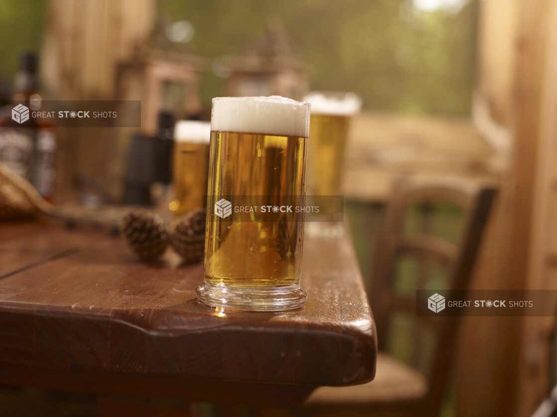 A Large Pint of Draught Beer on a Wooden Table with Assorted Sized Glasses of Beer in an Indoor Setting