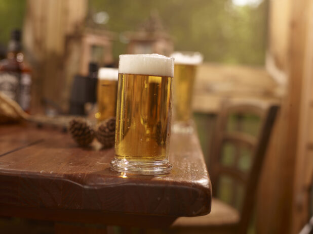 A Large Pint of Draught Beer on a Wooden Table with Assorted Sized Glasses of Beer in an Indoor Setting