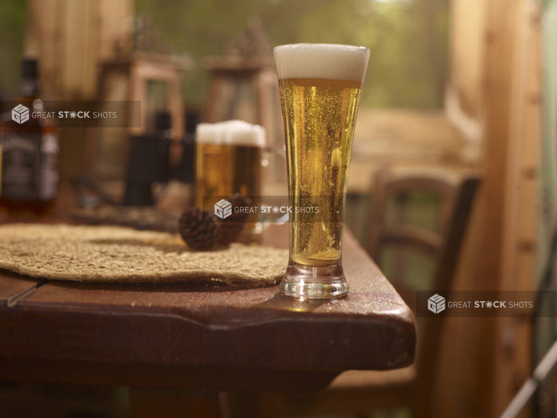 Close Up of a Pilsner Glass of Draught Beer on a Woven Placemat and Wooden Table in an Indoor Setting