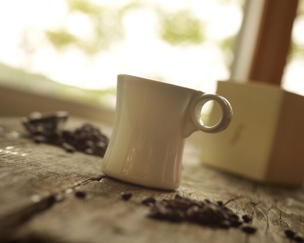 Ceramic Coffee Mug on a Aged Wooden Table with Coffee Beans in an Indoor Setting