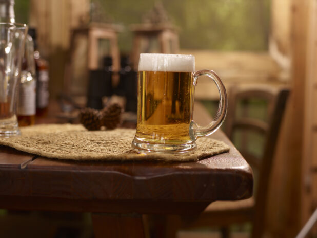 Close Up of Glass Stein of Draught Beer on a Woven Placemat and Wooden Table in an Indoor Setting