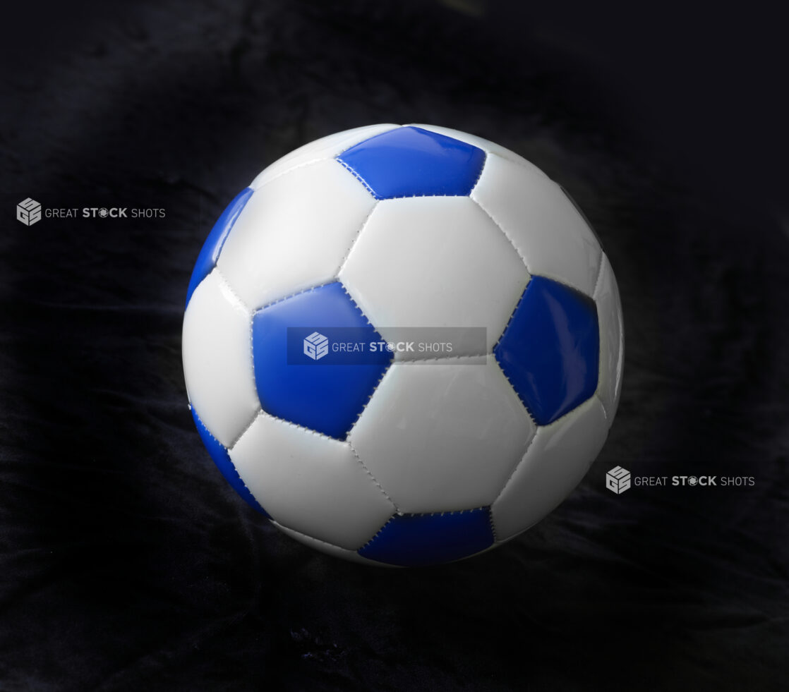 A Blue and White Soccer Ball (Football Ball) Isolated Against a Black Background