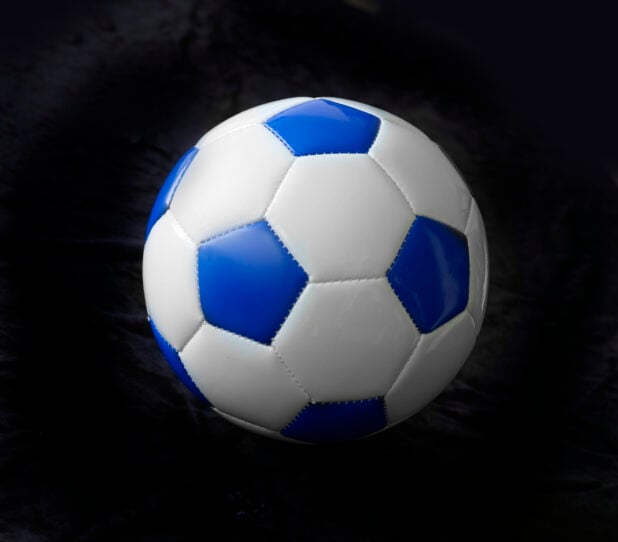 A Blue and White Soccer Ball (Football Ball) Isolated Against a Black Background