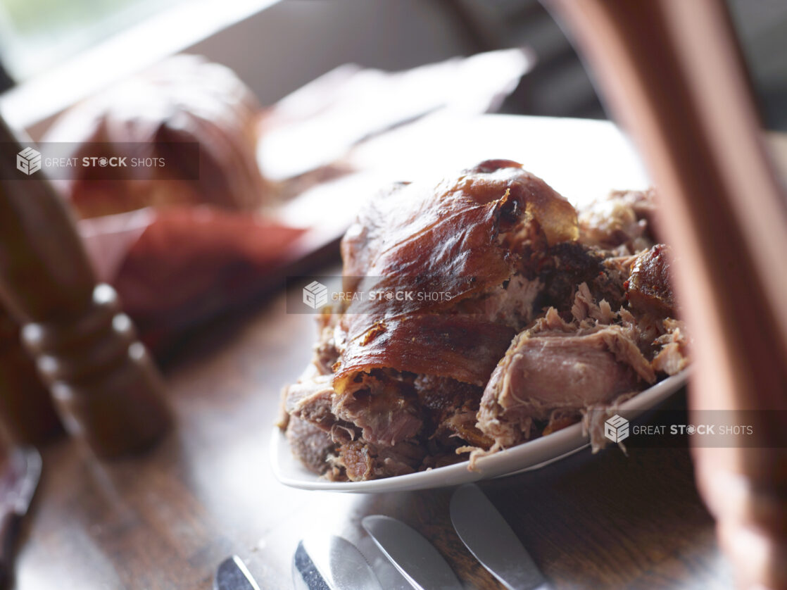 Close Up of Carved Porchetta Roast on White Platter with Bokeh Effect