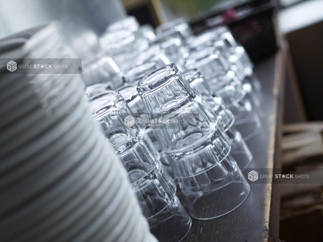 Clean Stacks of Water Glasses and White Dinner Plates with Bokeh Effect