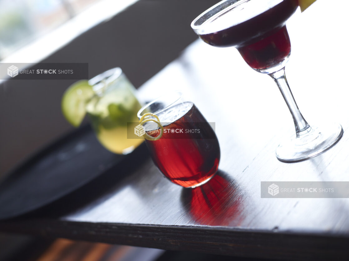 Cocktail with Citrus Peel Twist Garnish on Dark Wooden Table with Other Assorted Drinks - variation