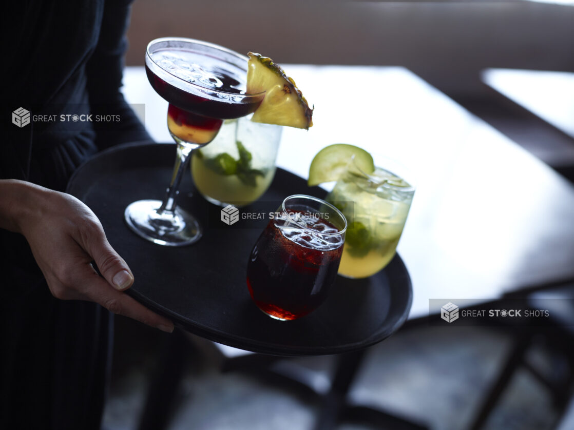 Server Carrying Assorted Cocktails on a Tray in a Restaurant Indoor Setting