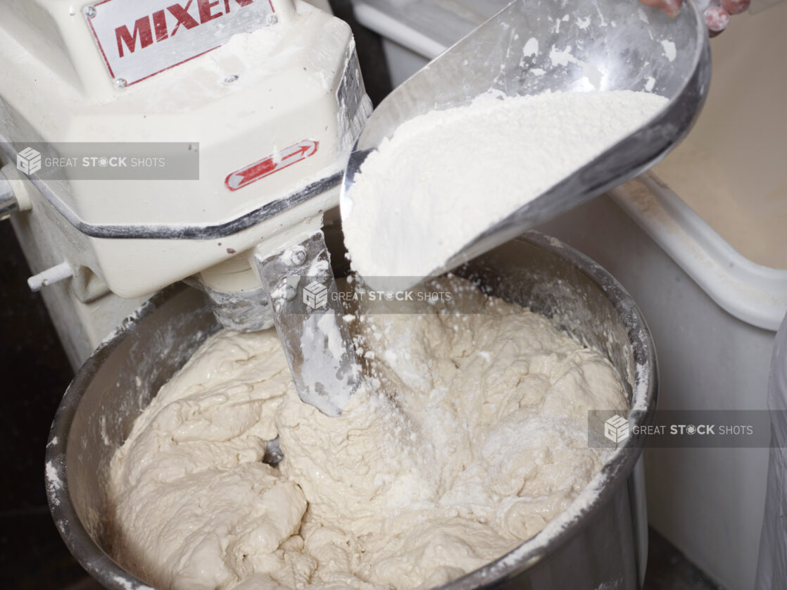 Person Adding Flour to Pizza Dough Mixing Machine