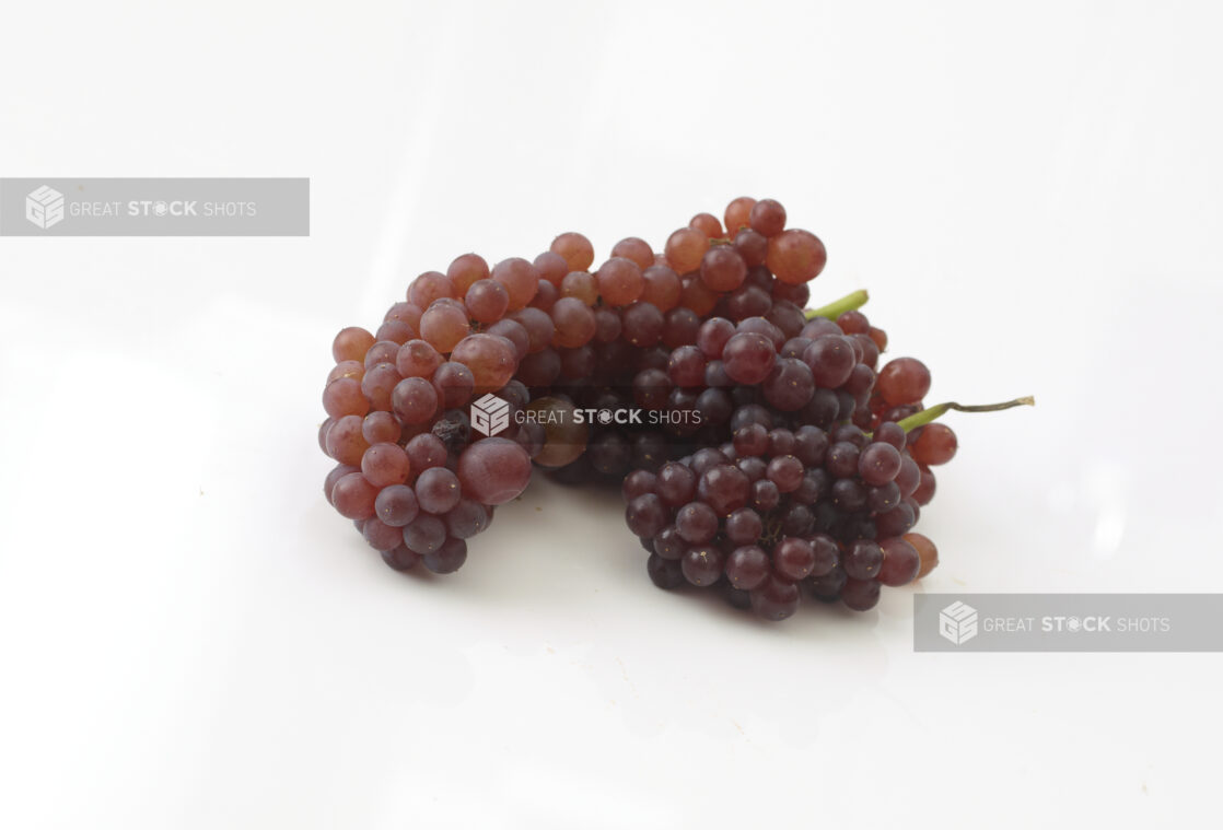 Whole red grapes in a bunch in a close up view on a white background