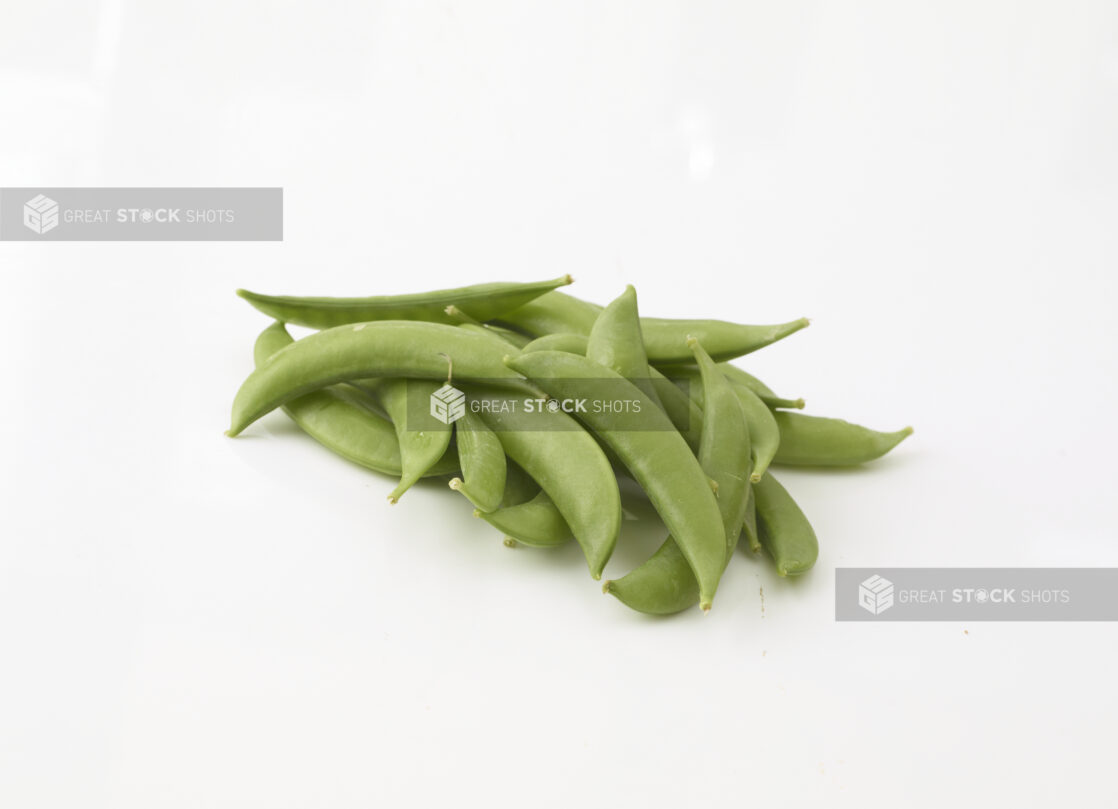 Whole snap peas in a grouping on a white background in a close up view