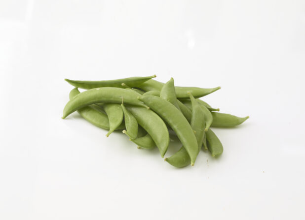 Whole snap peas in a grouping on a white background in a close up view