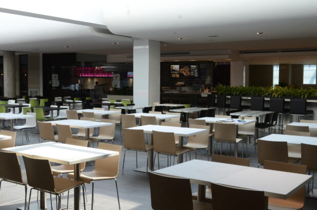 Empty sunlit food court with white tables, neutral palette