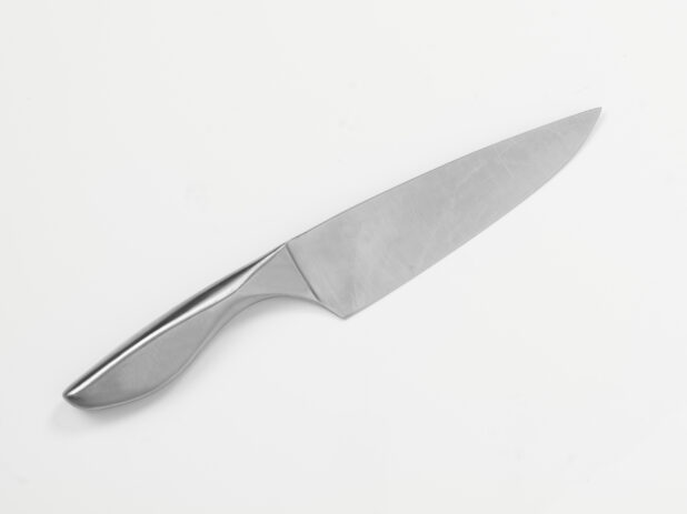 One-piece steel chef's knife on white background, close-up