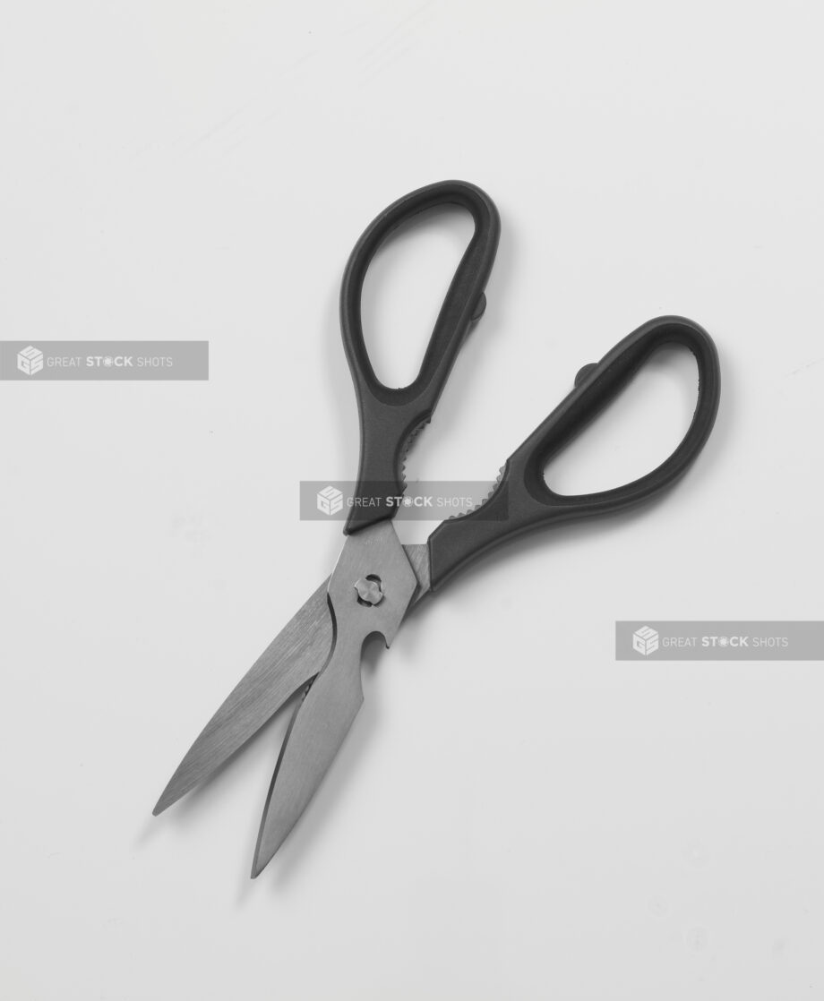 Pair of black-handled kitchen utility scissors on white background