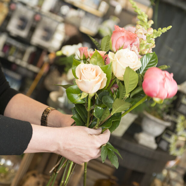 Woman's hands holding a bouquet of freshly roses, tulips and snapdragons