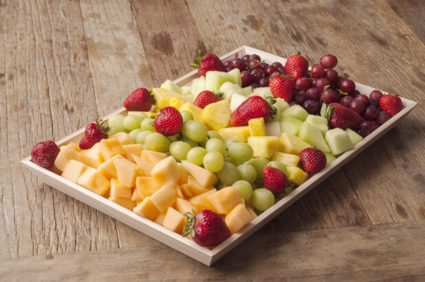 Fresh fruit on a wooden tray on a rustic wooden table