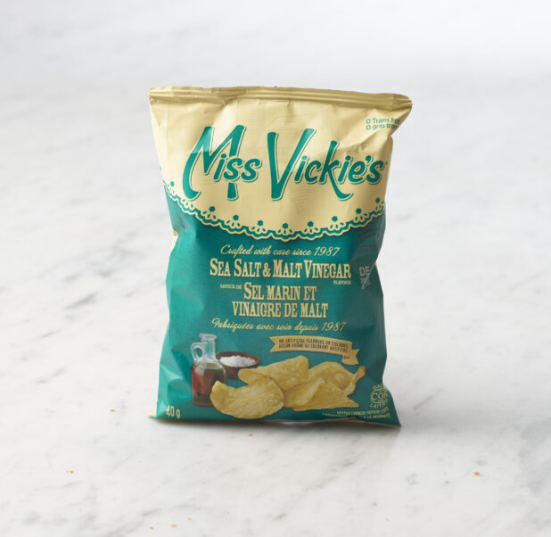 Individual bag of Miss Vickie's salt and malt vinegar chips on marble background