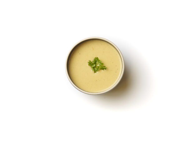 Overhead View of a Bowl of Lentil and Swiss Chard Vegan Soup with a Fresh Parsley Garnish, on a White Background for Isolation