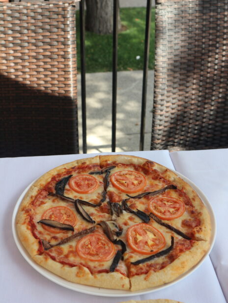 Medium tomato and portobello mushroom pizza on a white table cloth on an outdoor patio at a restaurant