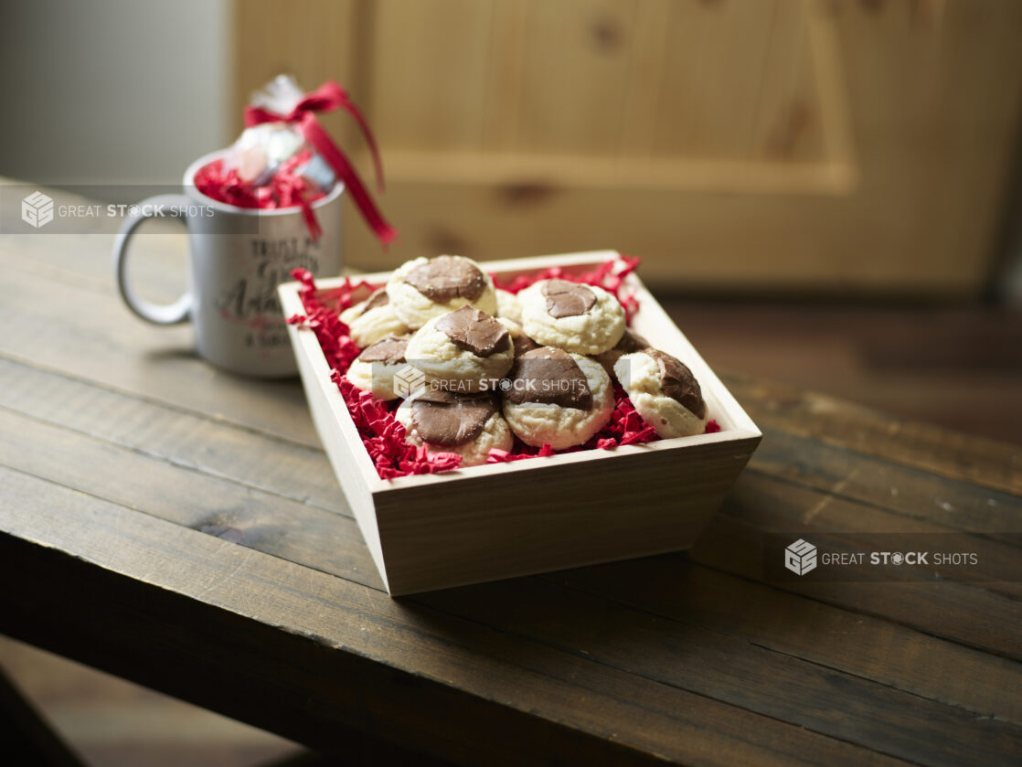 A Valentine's Day gift box with shortbread cookies chocolate and an accompanying mug on a dark wooden table