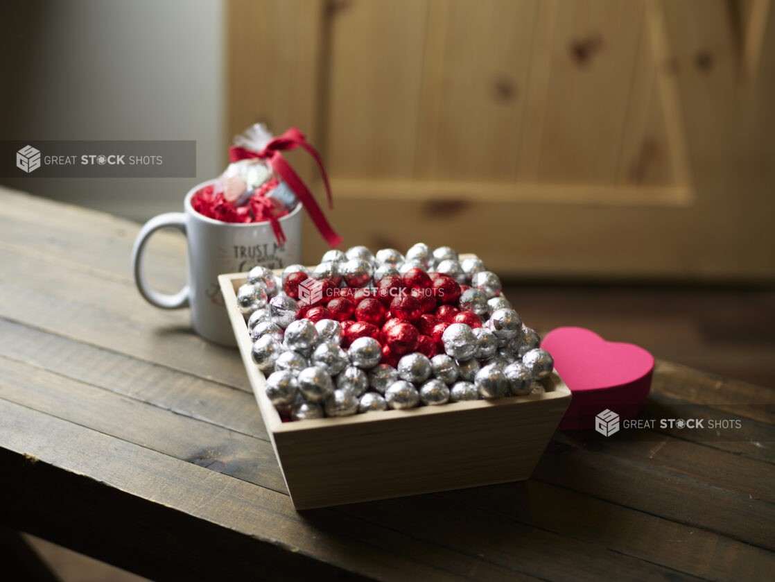 A Wooden gift box with chocolate foil balls for Valentine's Day with accompanying mug