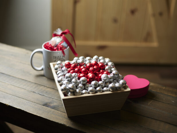 A Wooden gift box with chocolate foil balls for Valentine's Day with accompanying mug