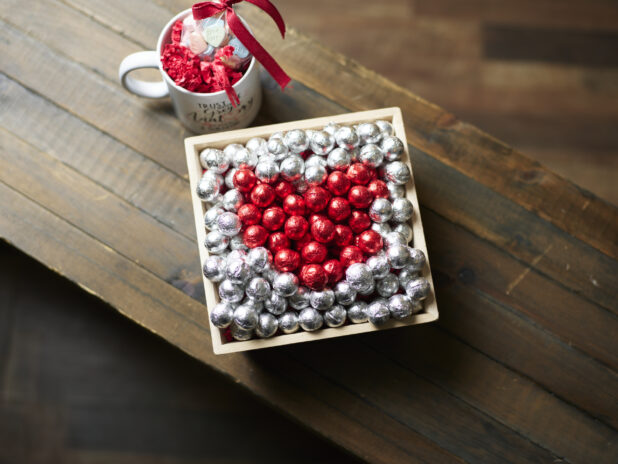 A Valentine's Day gift box with red and silver chocolate foil balls and accompanying mug