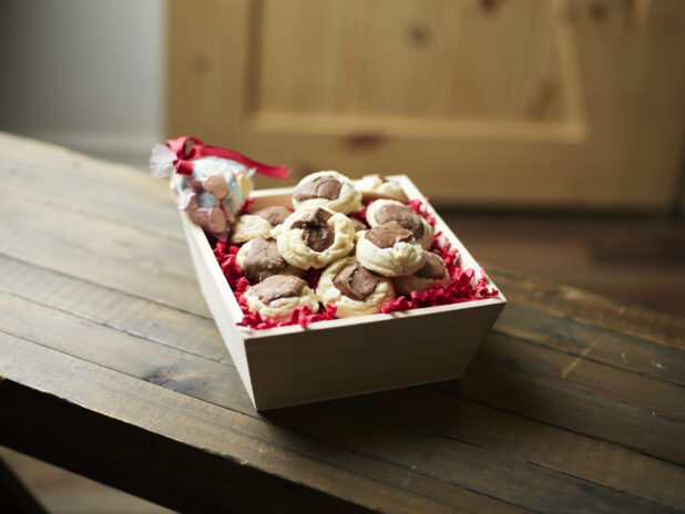 Valentine's Day gift box with chocolate shortbread cookies and candy hearts on a dark wooden table