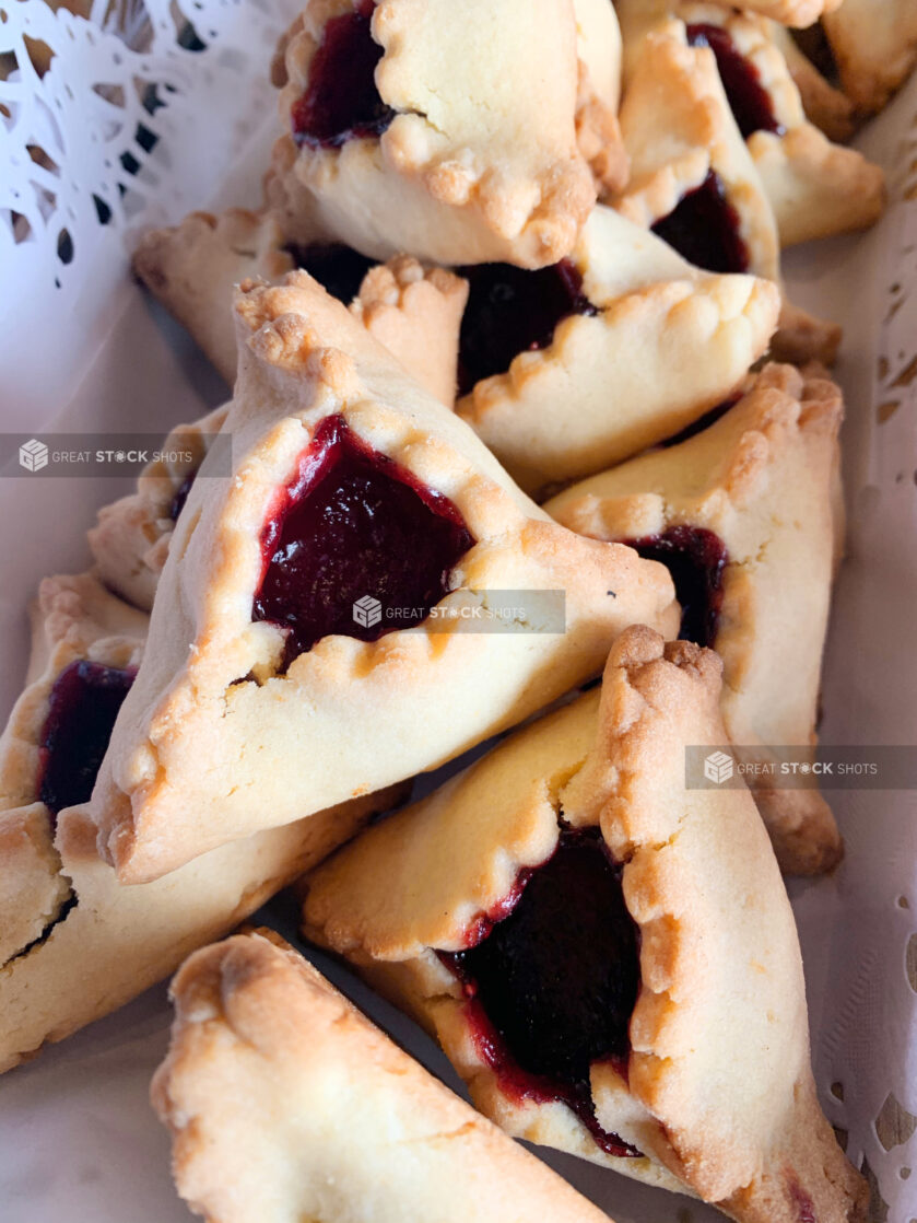 Close Up of Traditional Jewish Hamantaschen Pastries with Poppyseed Paste Filling on a Doily Lined Platter