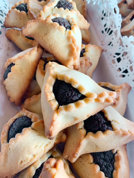 Close Up of Traditional Jewish Hamantaschen Pastries with Poppyseed Paste Filling on a Doily Lined Platter