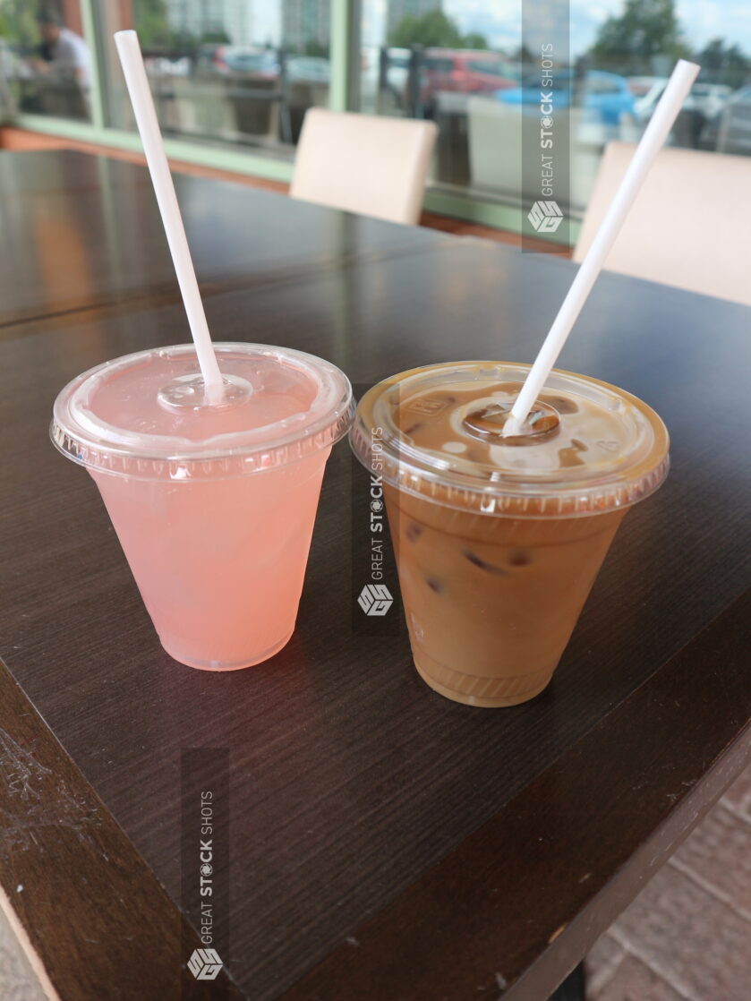 Two cold beverages with on a wooden table outside on a patio