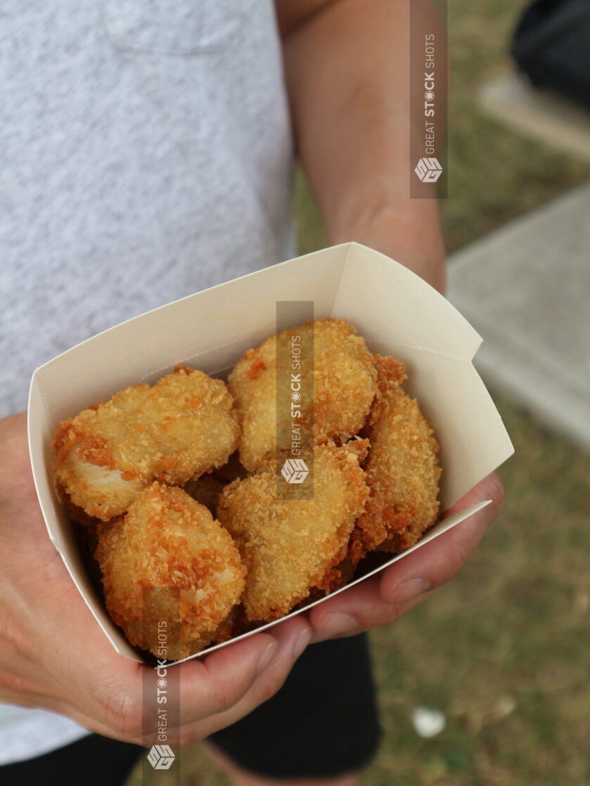 Overhead of person holding a take out container full of chicken nuggets outside