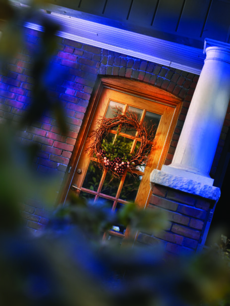 View of a Typical Brick American Home's Wooden Front Door with a Christmas Wreath Decoration in an Outdoor Winter Setting