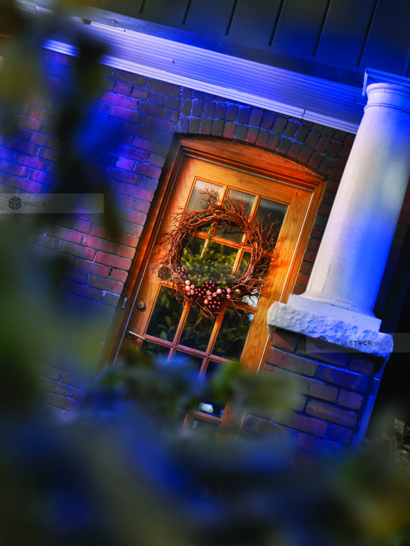 View of a Typical Brick American Home's Wooden Front Door with a Christmas Wreath Decoration in an Outdoor Winter Setting