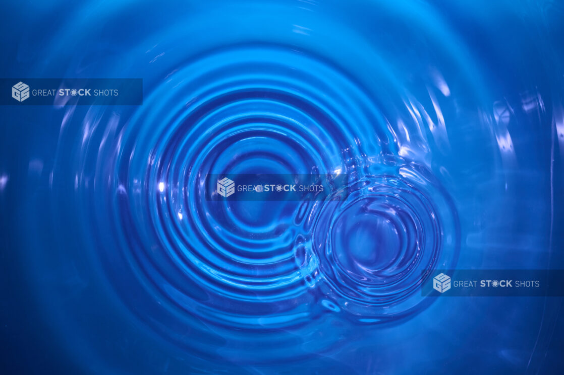 Overhead Close Up View of Water Droplets Creating Ripples in Clear Blue Water