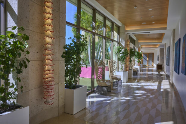 Outer Hallway of a Resort Hotel with Floor to Ceiling Windows, Potted Indoor Trees and Tall Back Wicker Chairs in Nassau, Bahamas