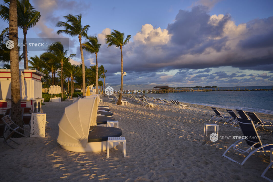 Rows of Beach Chairs and Domed Tents Facing Turquoise Waters on a White Sandy Beach in a Resort in Nassau, Bahamas - side view