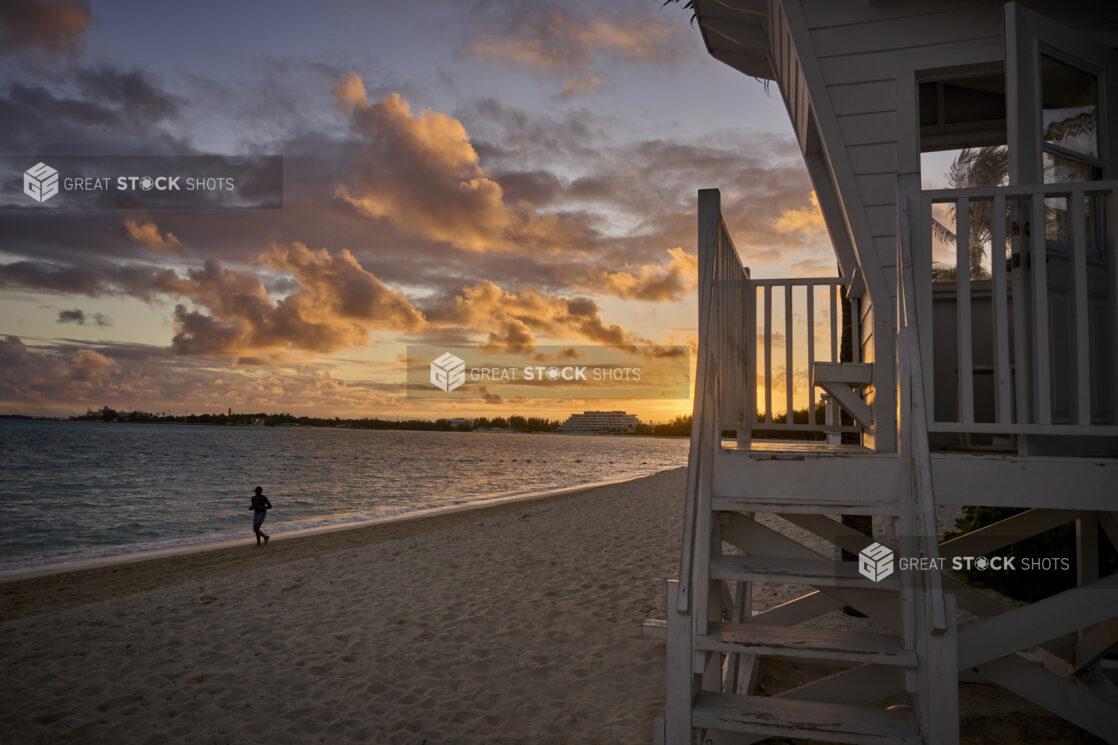 Landscape View of a Sandy Tropical Beach and Beach House at Sunset or Sunrise with a Silhouette of a Lone Jogger in Nassau, Bahamas