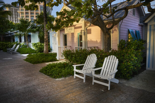 White Wooden Deck Chairs on a Boardwalk in Front of Painted Wood Cabin Storefronts on a Hotel Property in Nassau, Bahamas