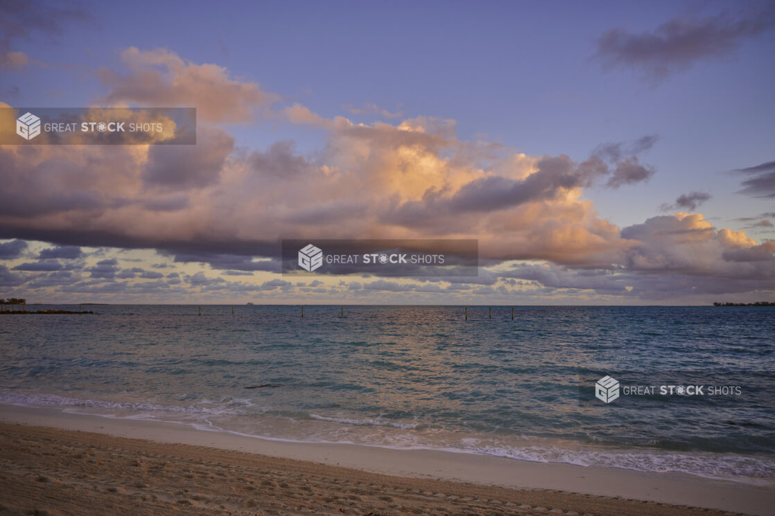 Shoreline View of a Row of Clouds Forming Over the Blue Waters of a Sandy Beach at Sunset or Sunrise in Nassau, Bahamas