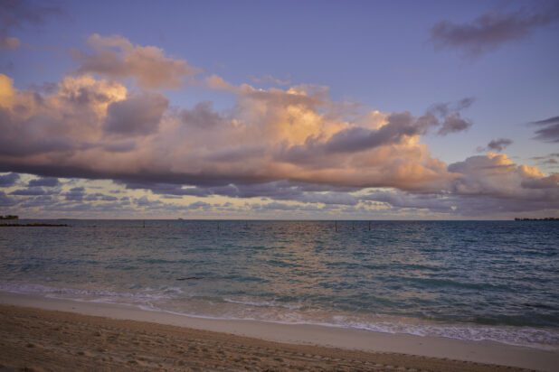Shoreline View of a Row of Clouds Forming Over the Blue Waters of a Sandy Beach at Sunset or Sunrise in Nassau, Bahamas